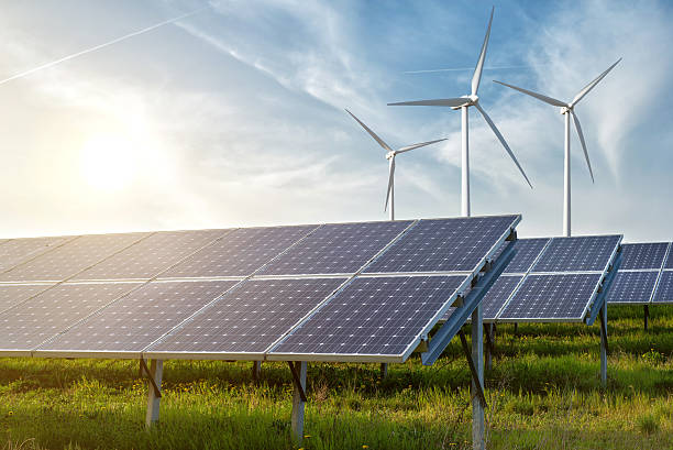 Solar panels and wind turbines in a field, illustrating renewable energy's influence on consumer electronics.